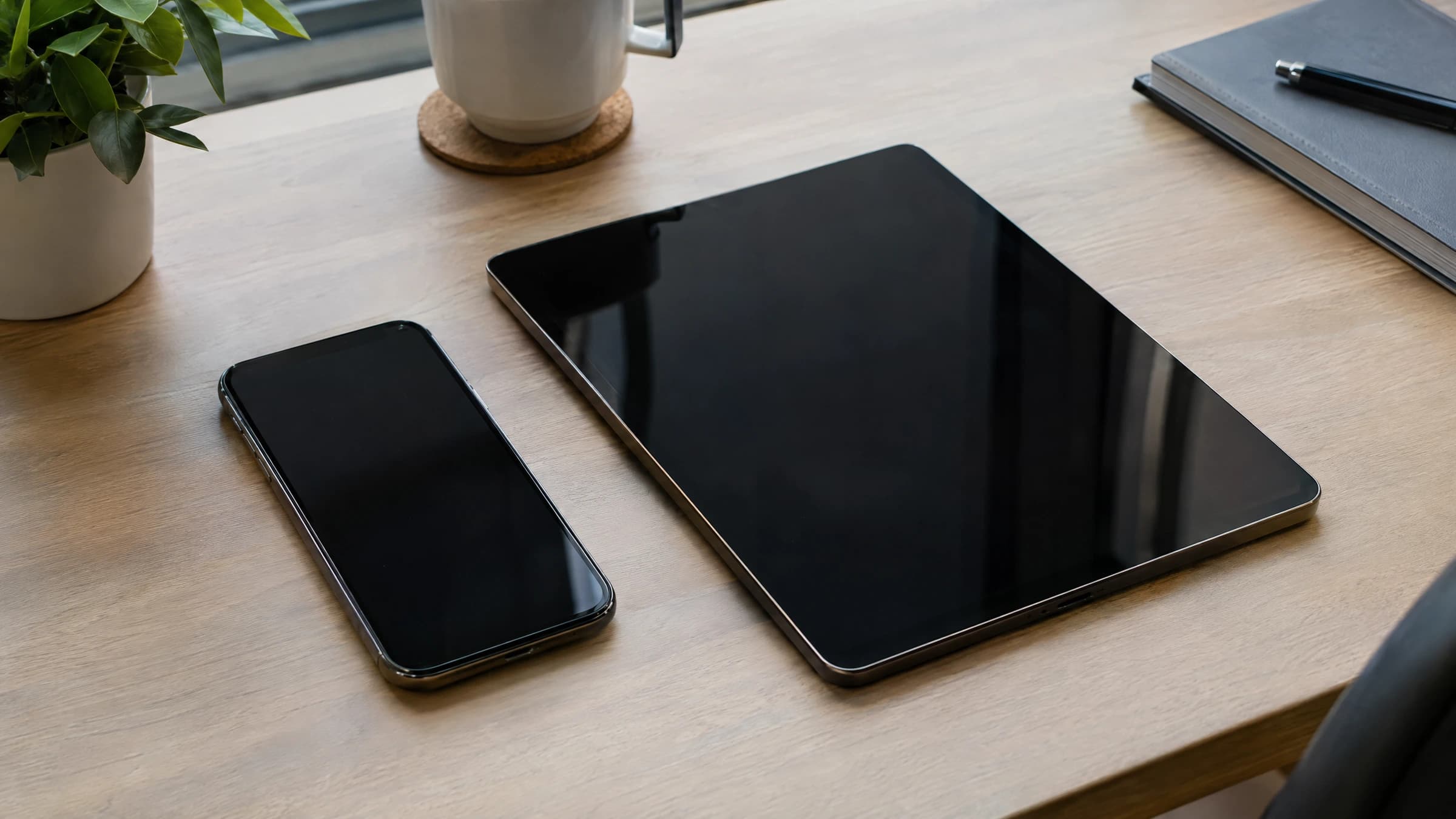 A powered-off phone and tablet on a home-office desk.