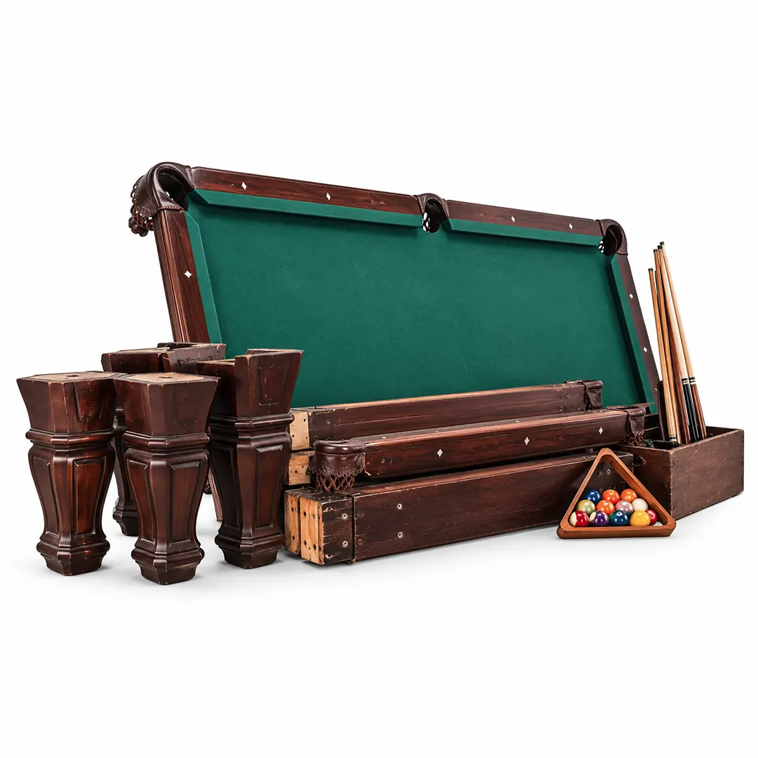 Disassembled pool table with green felt, carved legs, rails, cues and a rack of balls on a white background